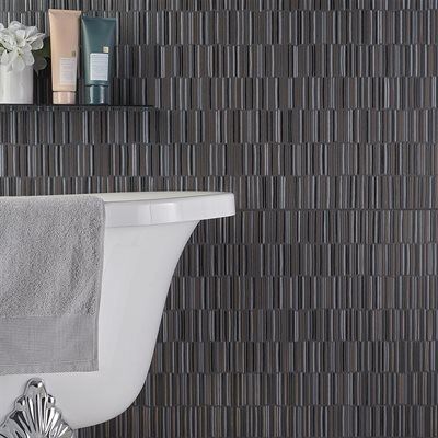 Bathtub with towel and toiletries shelf against a dark, vertical tile wall.