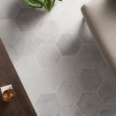 Hexagonal gray floor tiles, partially covered by a chair, table, and plant.