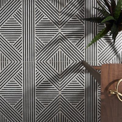 Black and white geometric tile wall with a plant and wooden cutting board.