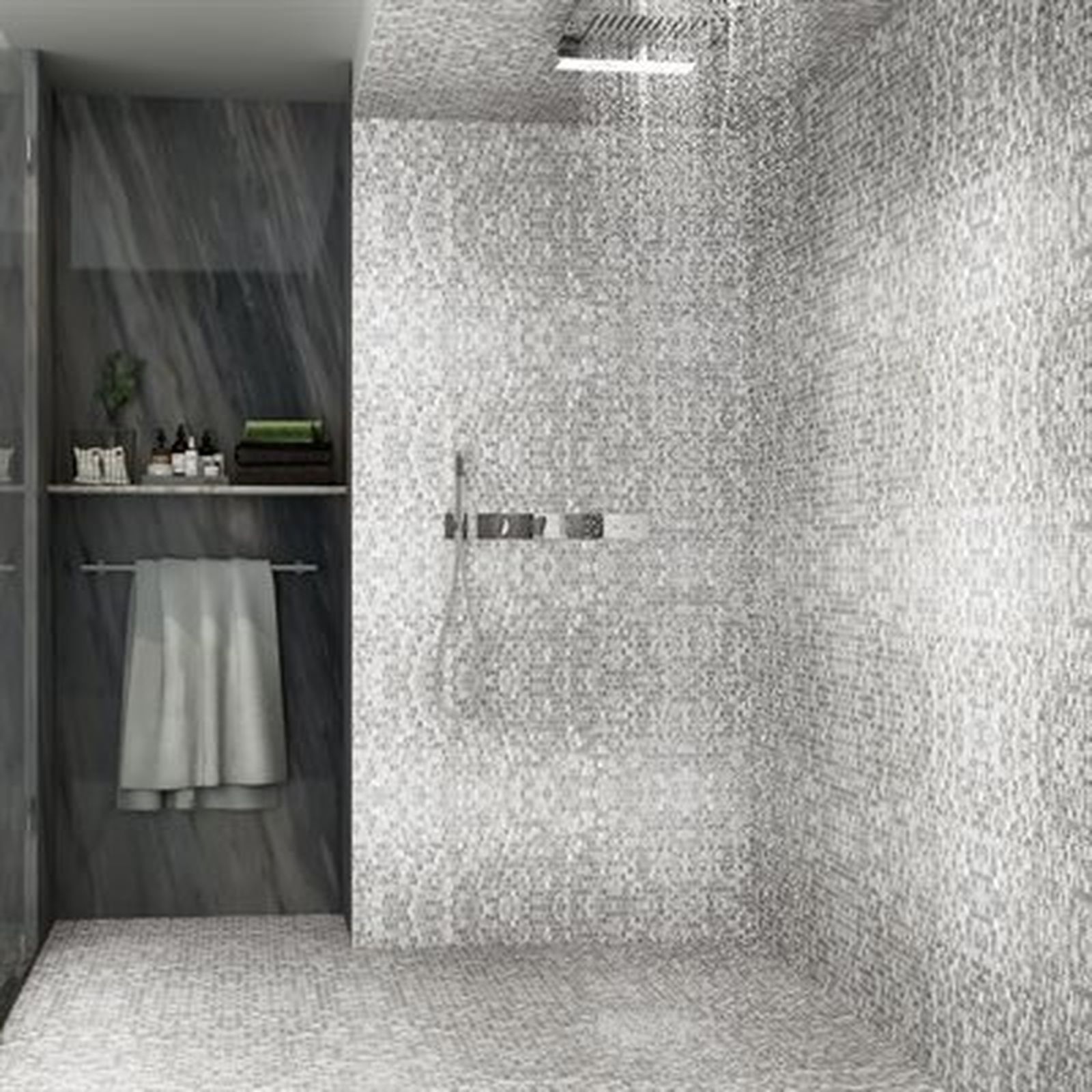 Gray tiled shower with overhead showerhead and built-in shelf for toiletries, towels on a rack.