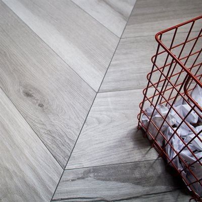 Herringbone wood floor with a reddish-brown wire basket filled with white paper.
