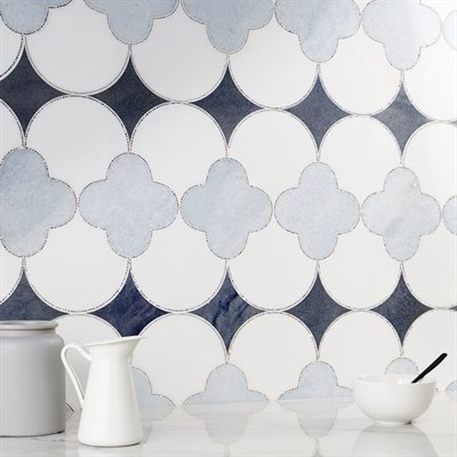 Blue and white patterned tile backsplash; white pitcher and bowl in foreground.