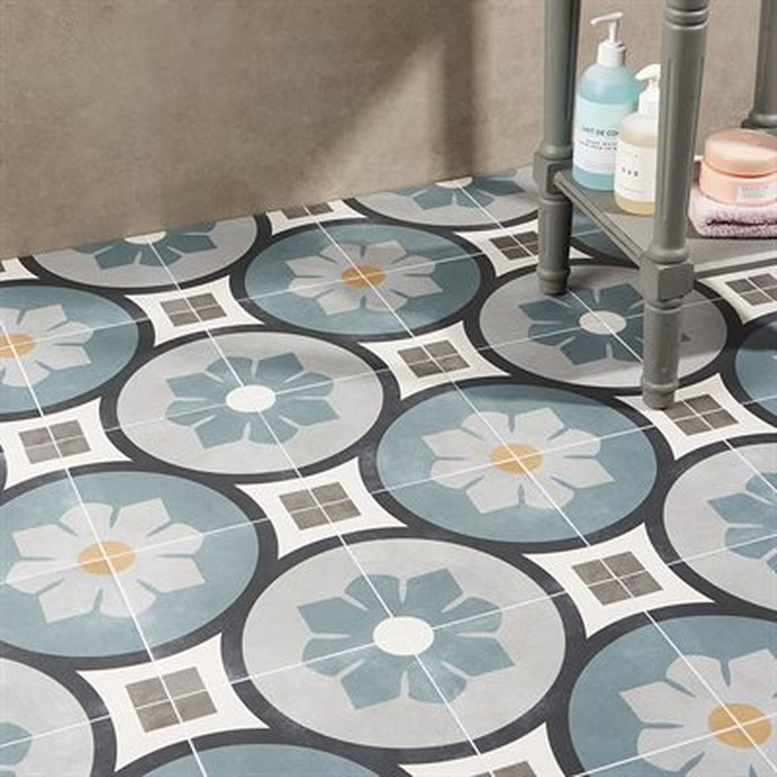 Bathroom floor with patterned tiles: blue, gray, and white floral designs and small square tiles.
