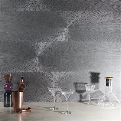 Cocktail bar with metallic textured wall, drinks, and glassware on a marble surface.