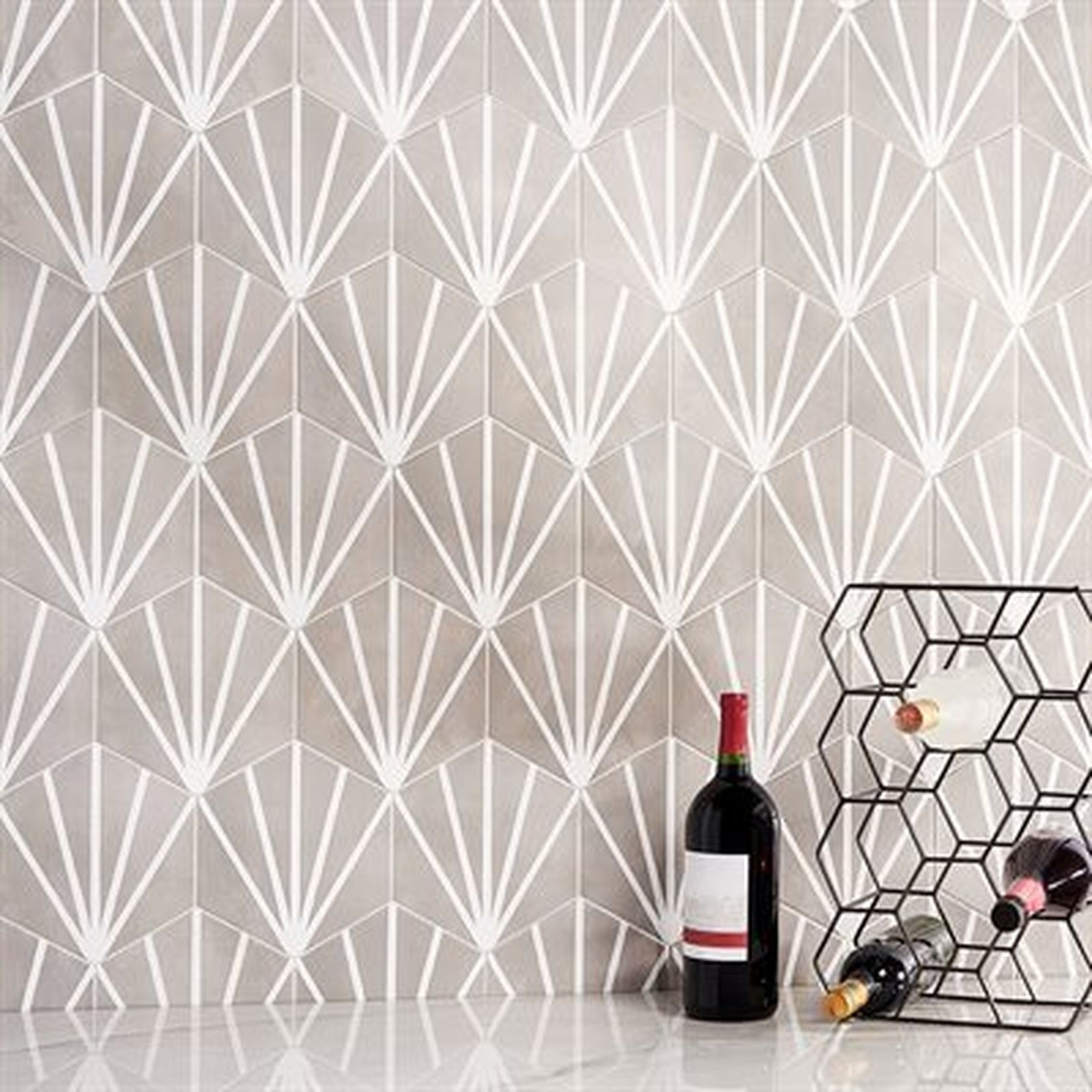 Gray and white fan-patterned tiles on a wall, with a wine rack and bottles of wine on a countertop.