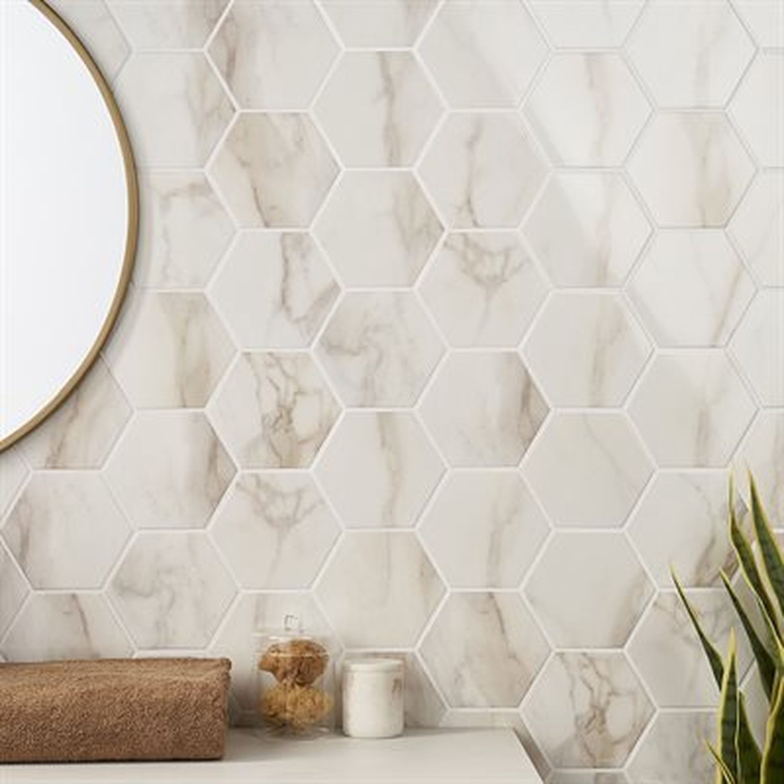 Hexagon marble tile backsplash in a bathroom, with a gold-rimmed mirror and a plant.