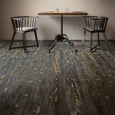 Rustic dining setting with black chairs and table, dark wood flooring.