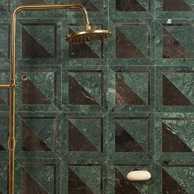 Shower with gold fixtures and green and brown tile. A bar of soap rests on the tiles.
