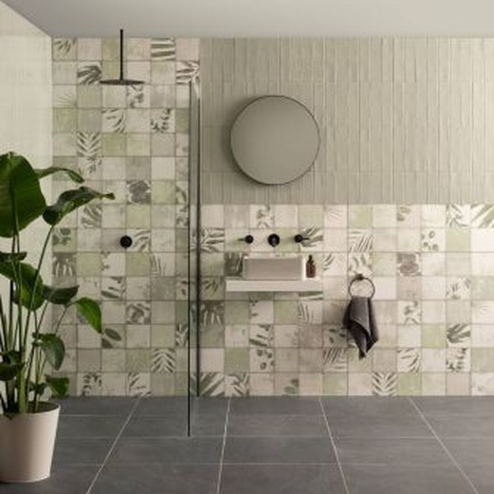 Bathroom with gray floor and walls; patterned tile shower, round mirror, and indoor plant.