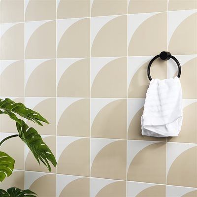 Geometric tile wall with a towel ring and a plant. Beige and white tiles.