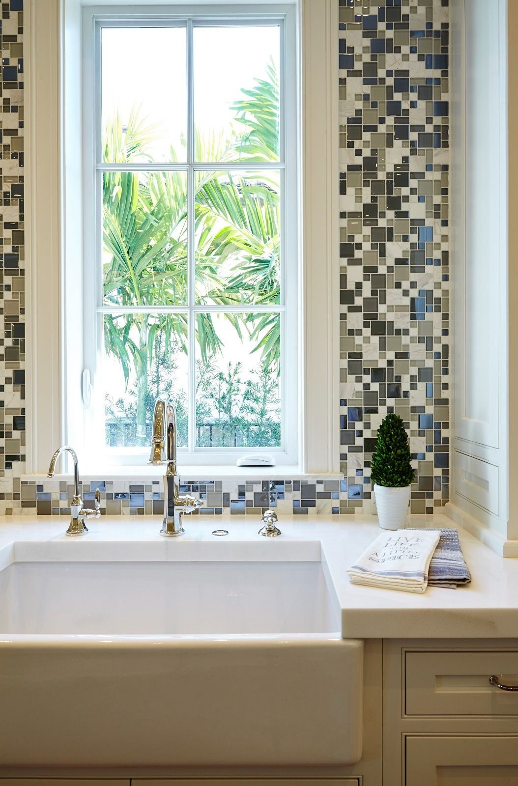 Kitchen sink with a window, mosaic tile backsplash, and white cabinetry.