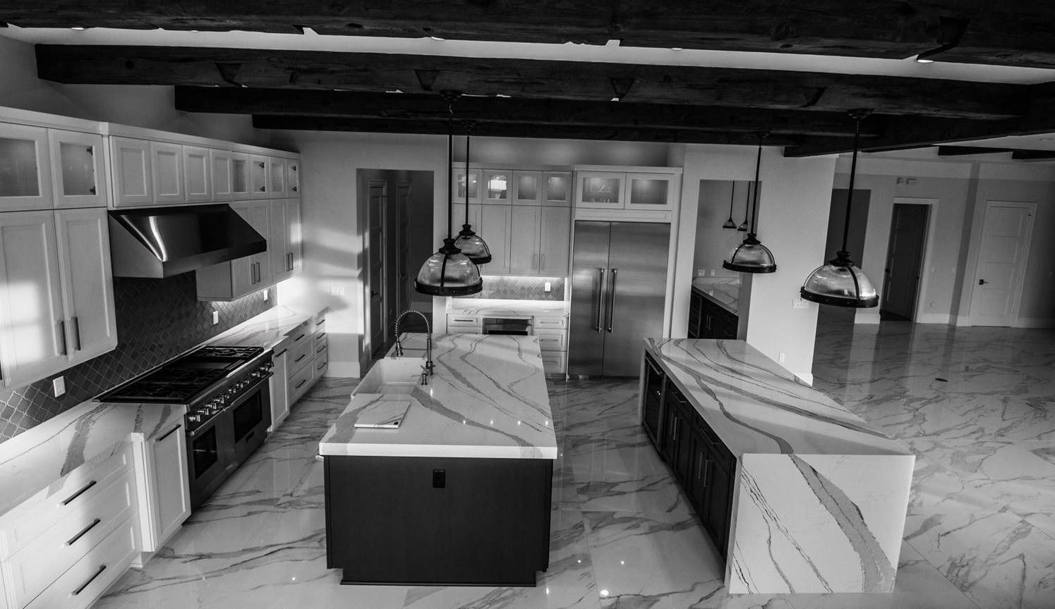 Black and white kitchen with two islands, cabinets, appliances, and overhead lighting.