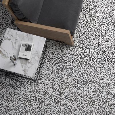 Black and white terrazzo floor with a modern armchair and marble coffee table.