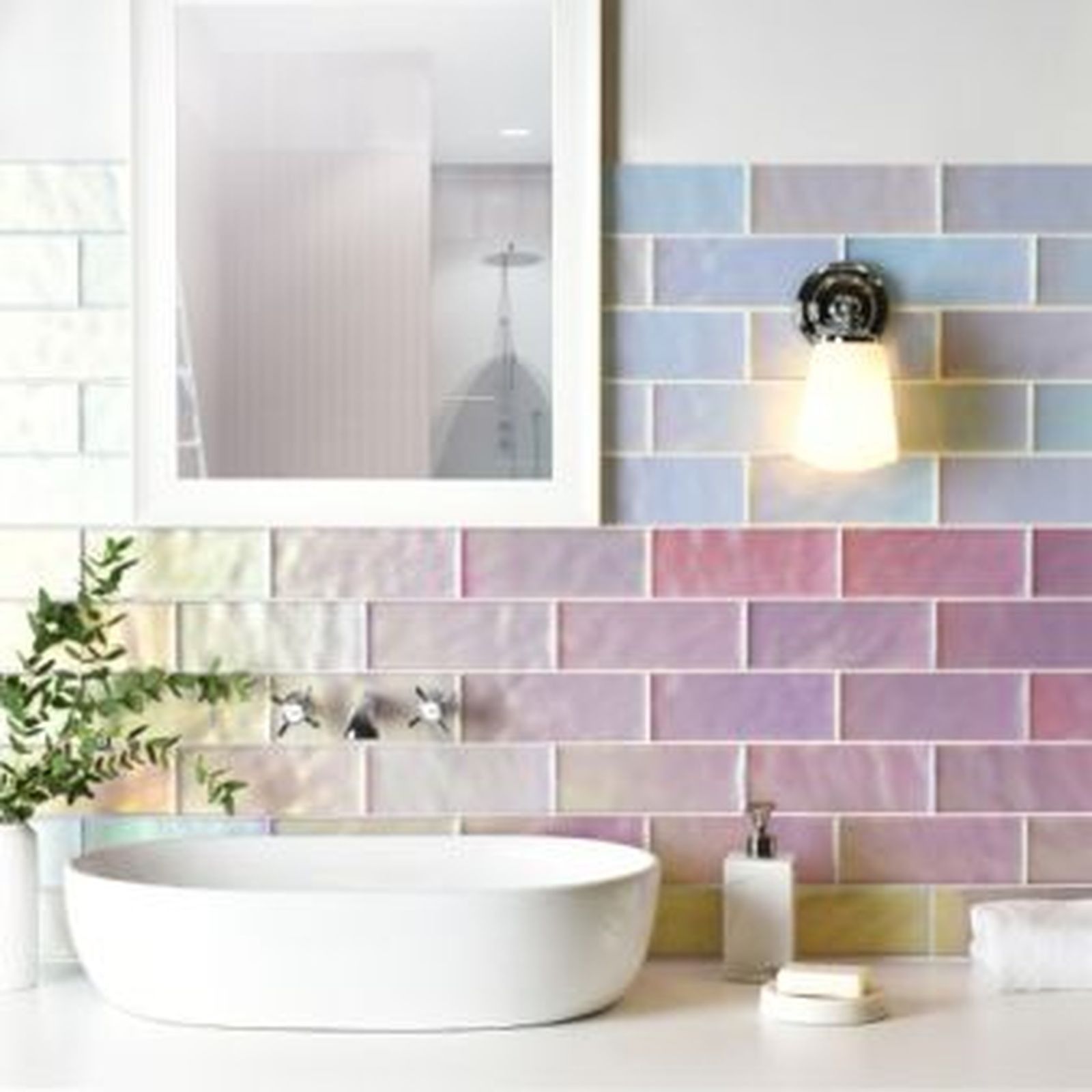 Bathroom with iridescent pastel tile backsplash, white sink, mirror, and light fixture.