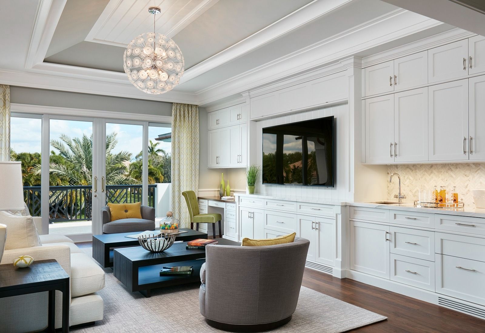 Living room with white cabinets, TV, sliding glass doors to a balcony, gray furniture, and decorative lighting.