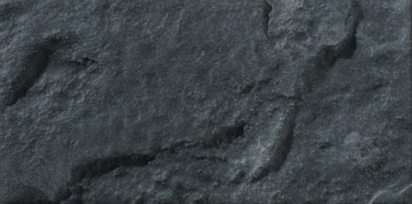 Close-up of a dark gray, textured stone surface with irregular shapes and rough details.