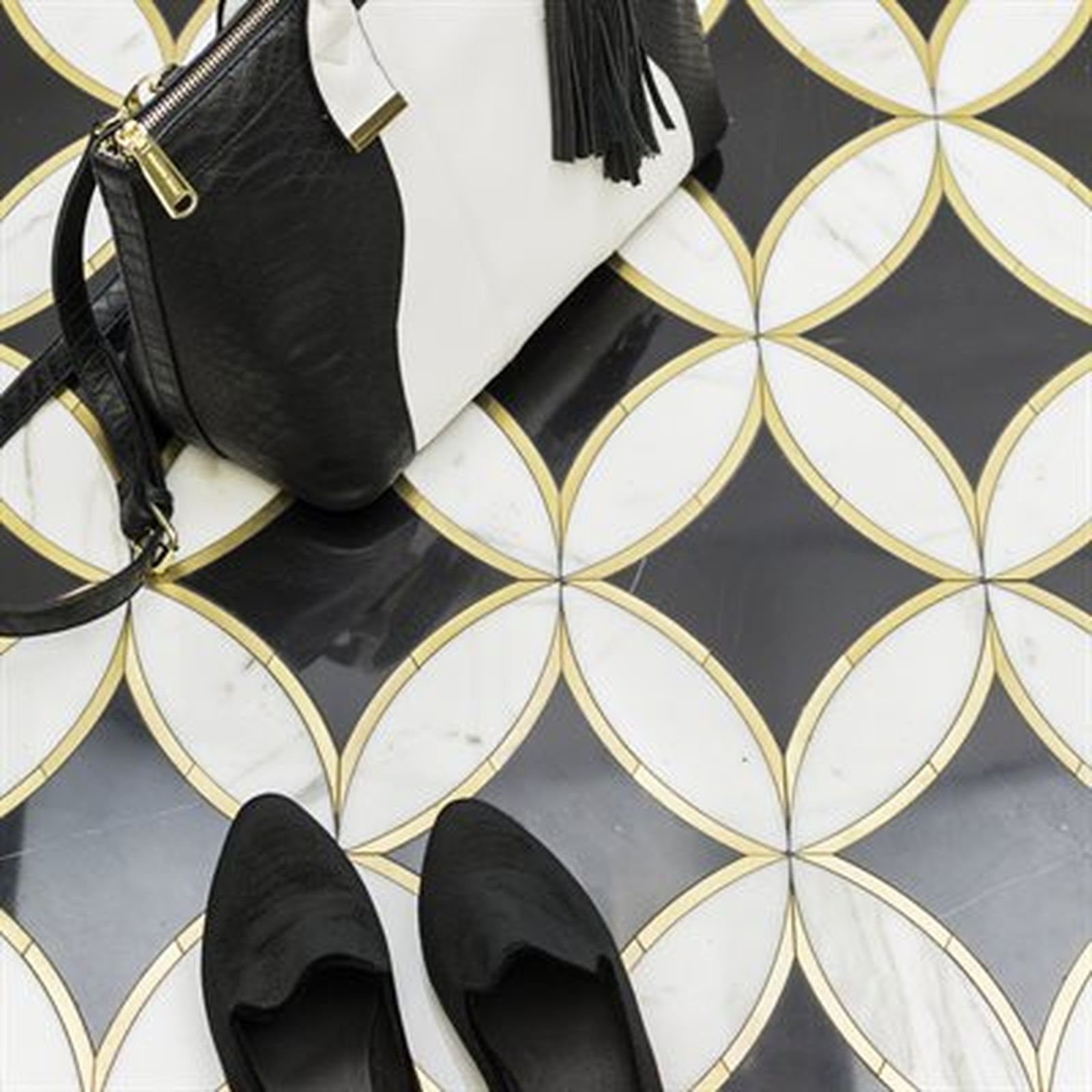 Black and white purse and shoes on a patterned tile floor with gold accents.