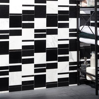 Black and white tile wall in a bathroom, with a metal shelf holding towels and toiletries.