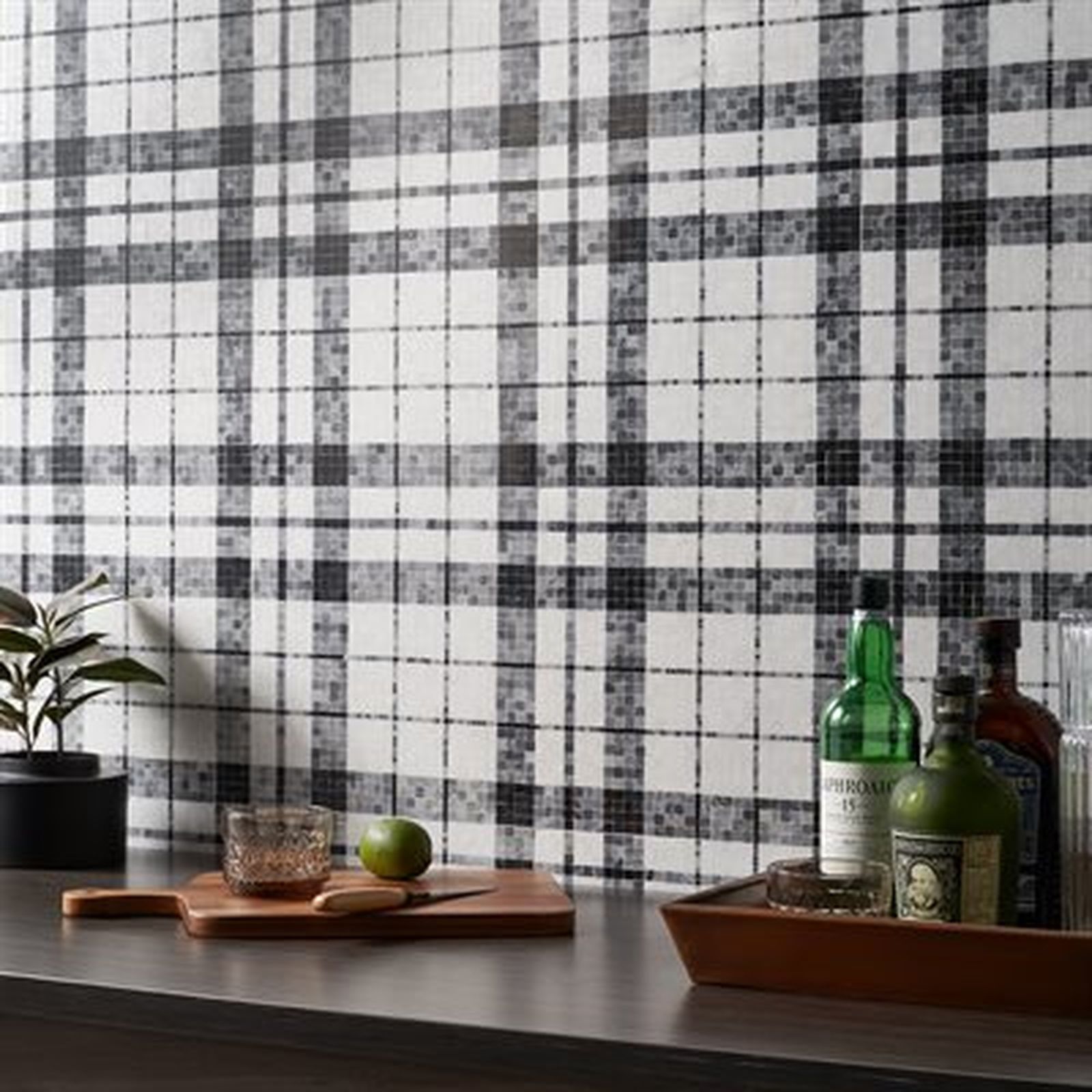 Black and white plaid wallpaper behind a countertop with a tray of liquor bottles and a cutting board.