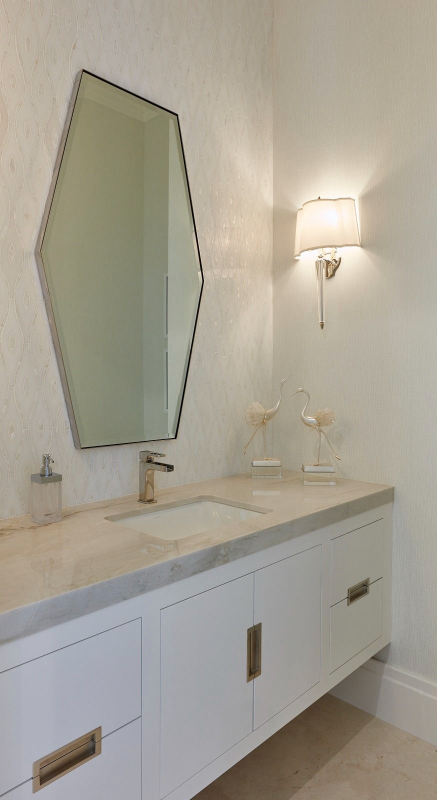 Bathroom with white vanity, unique mirror, sconce, and sink.