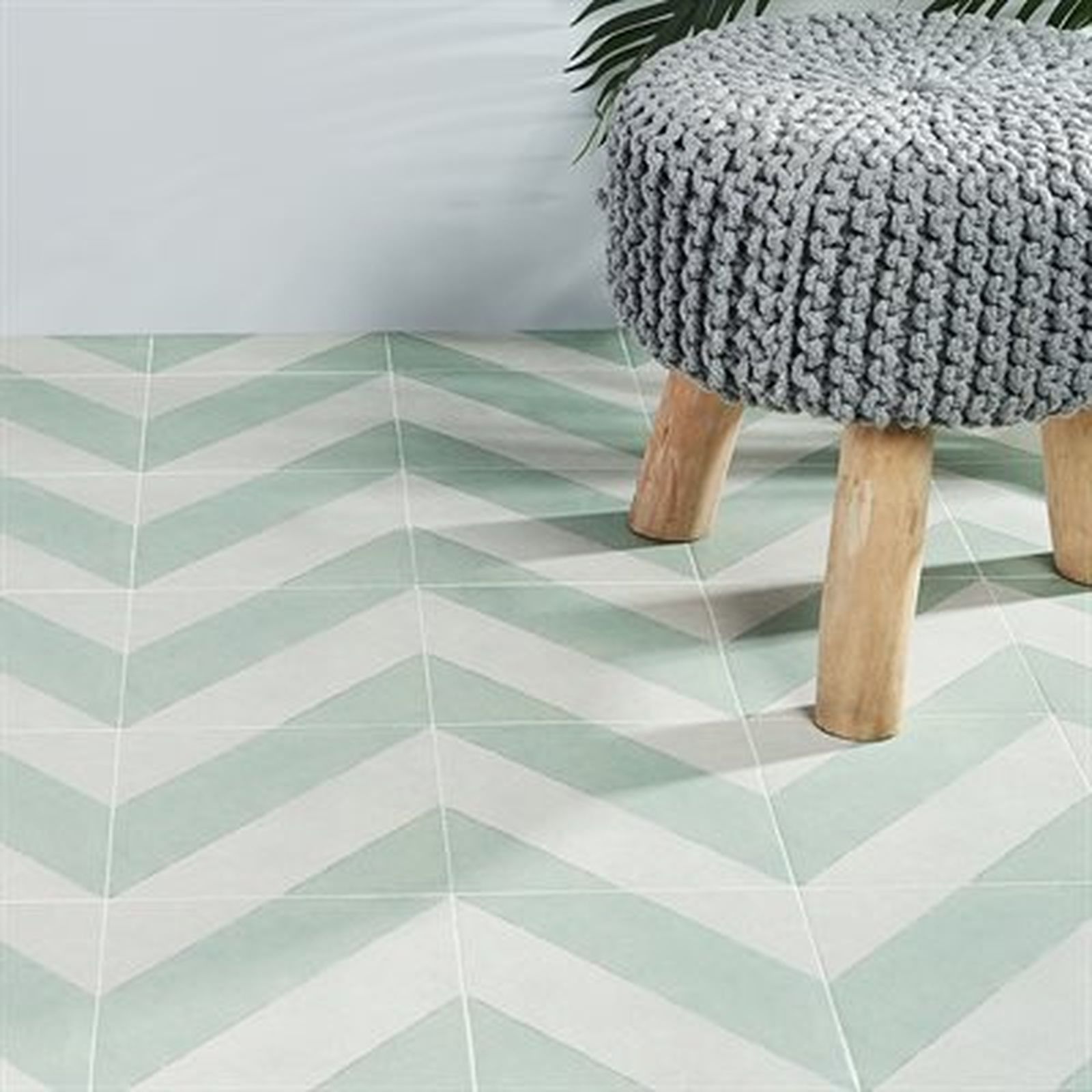 Light green and white chevron tiled floor with a gray knitted stool.