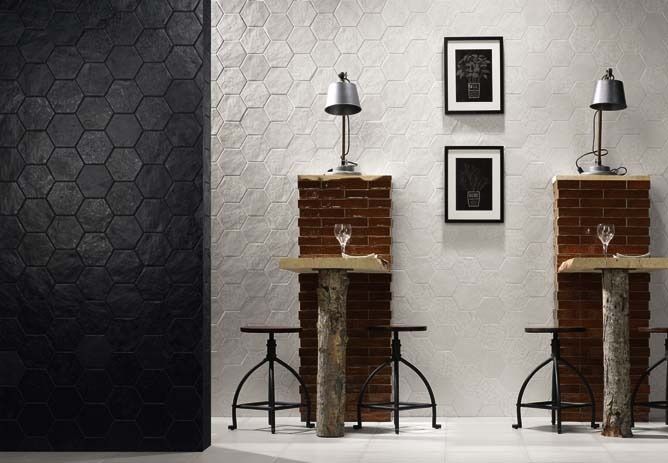 Modern bar scene with hexagon tile walls, wood and brick tables, lamps, stools, and framed art.