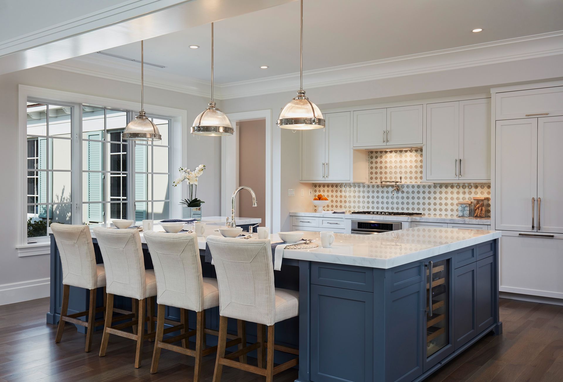 Elegant modern kitchen with blue island, white cabinets, and pendant lights.