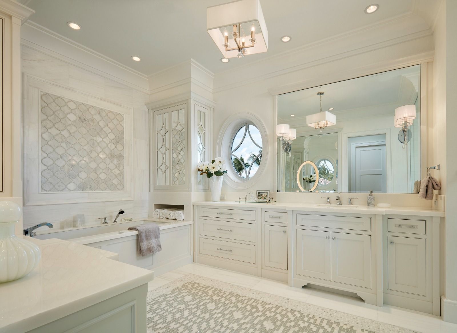 Elegant white bathroom with large mirror, vanity, and decorative tile.