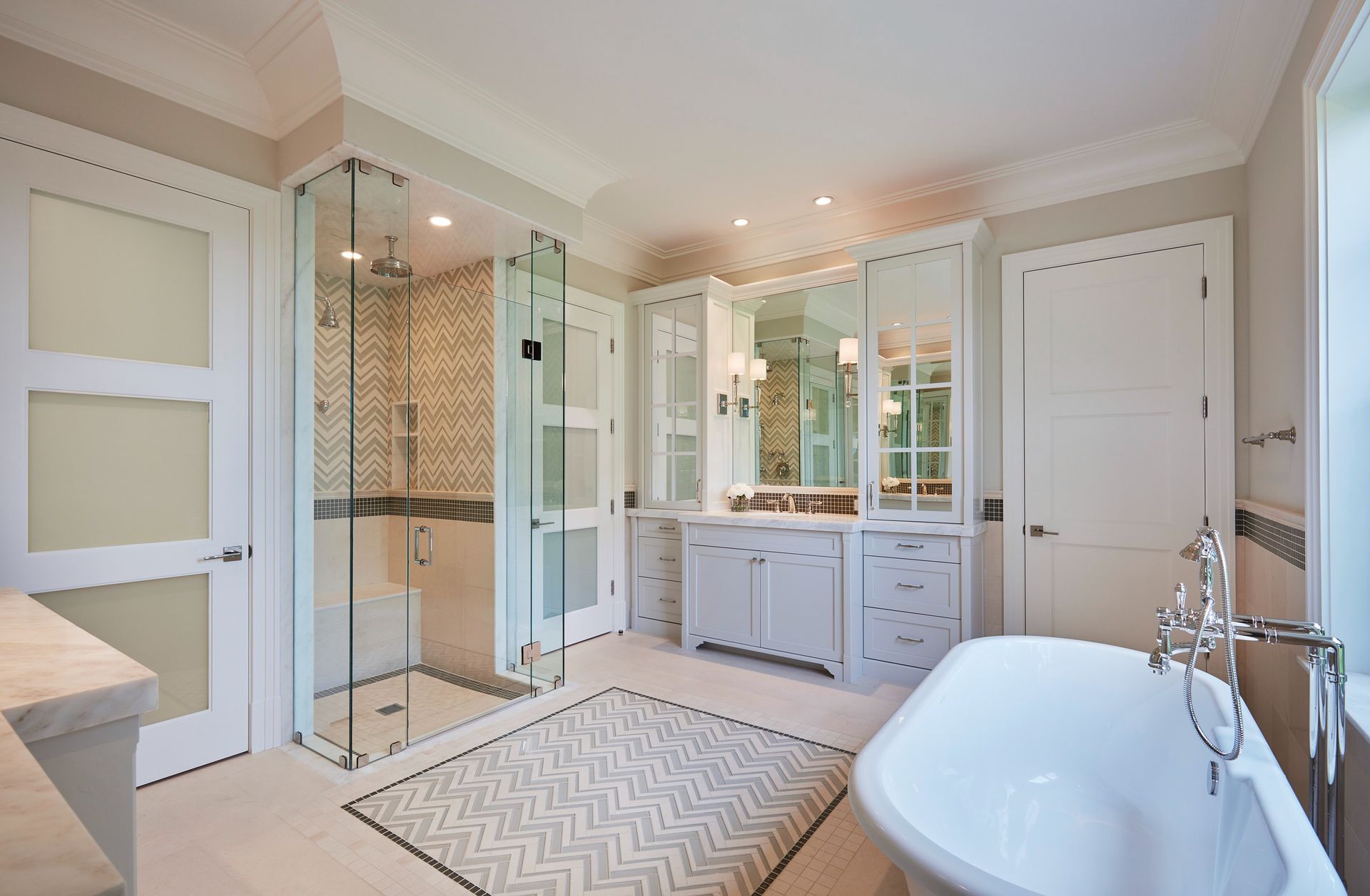 Elegant bathroom with glass shower, soaking tub, vanity, and white cabinets.