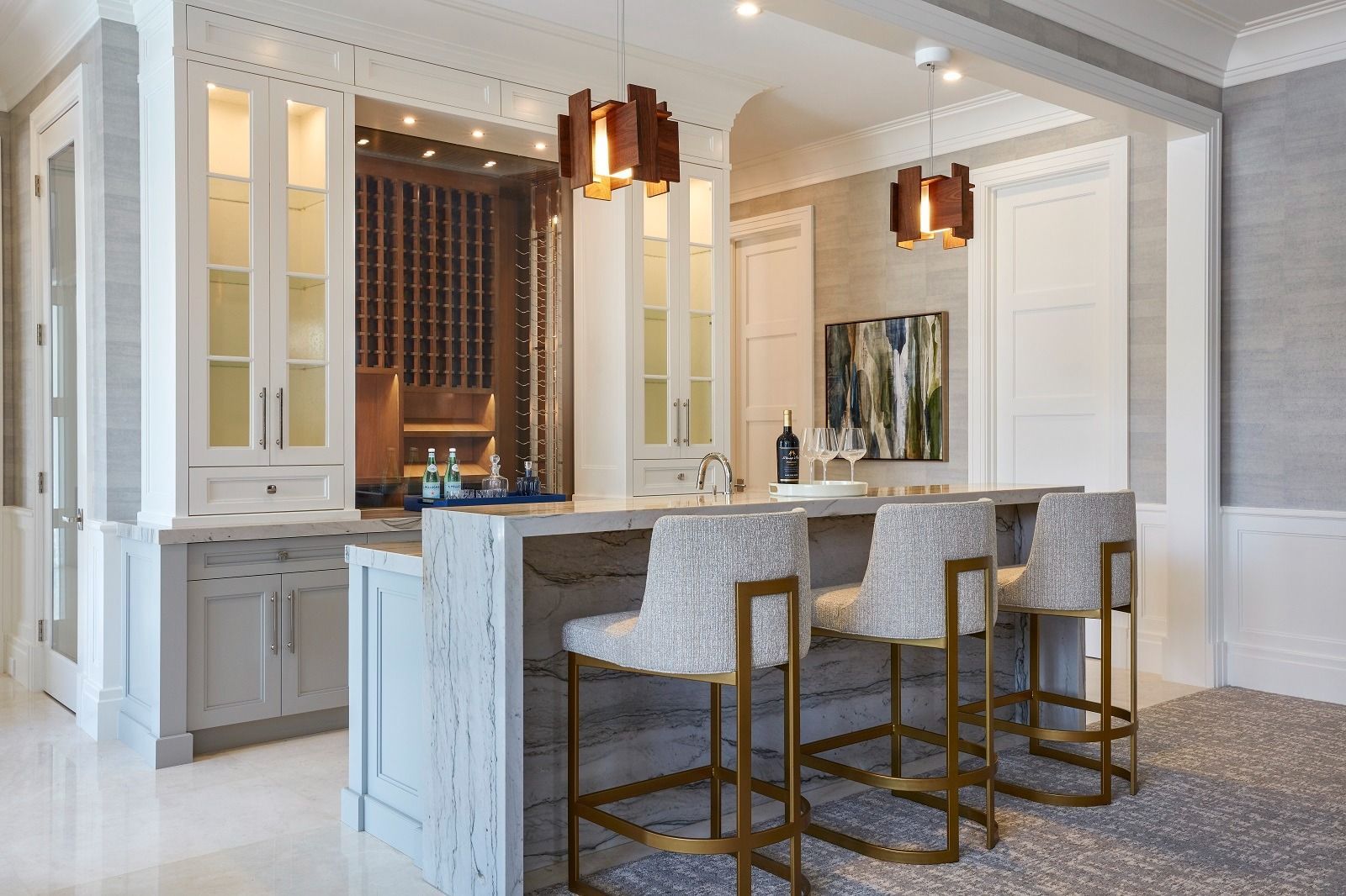 Bar with stools, cabinets, and a wine cellar, featuring light colors and modern decor.