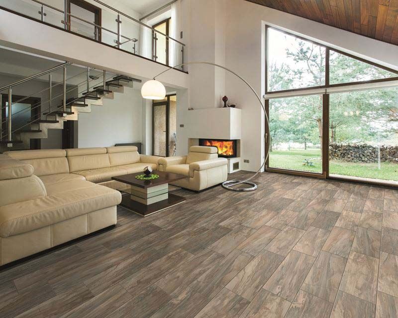 Living room with beige sofa, fireplace, hardwood floor, and large window overlooking a yard.