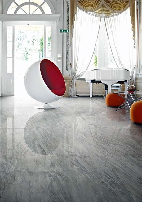 White and red spherical chair on reflective marble floor in a bright, elegant room with piano and open door.