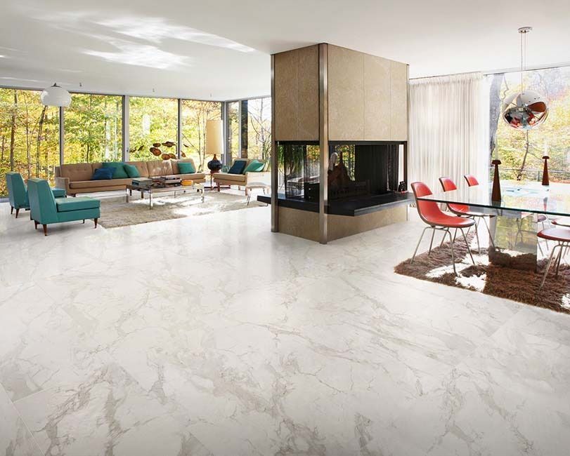 Modern living room with marble floors, fireplace, and large windows overlooking trees.