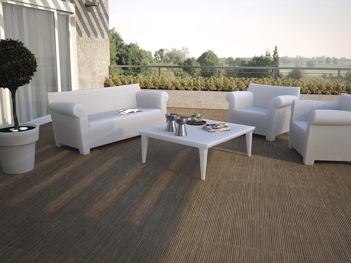 White patio furniture on a deck; sofa, armchairs, and coffee table. Overlooking a landscape, bright sunlight.