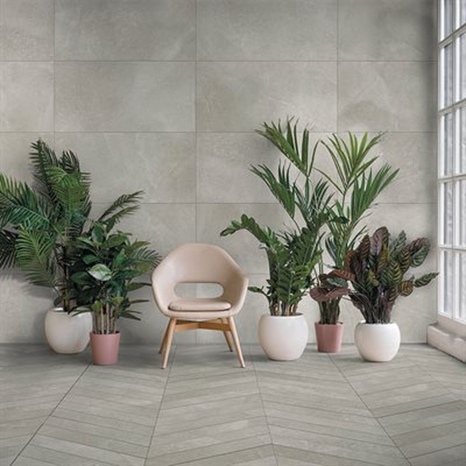 Indoor space with plants, chair, and gray tiled walls and floor, natural light.