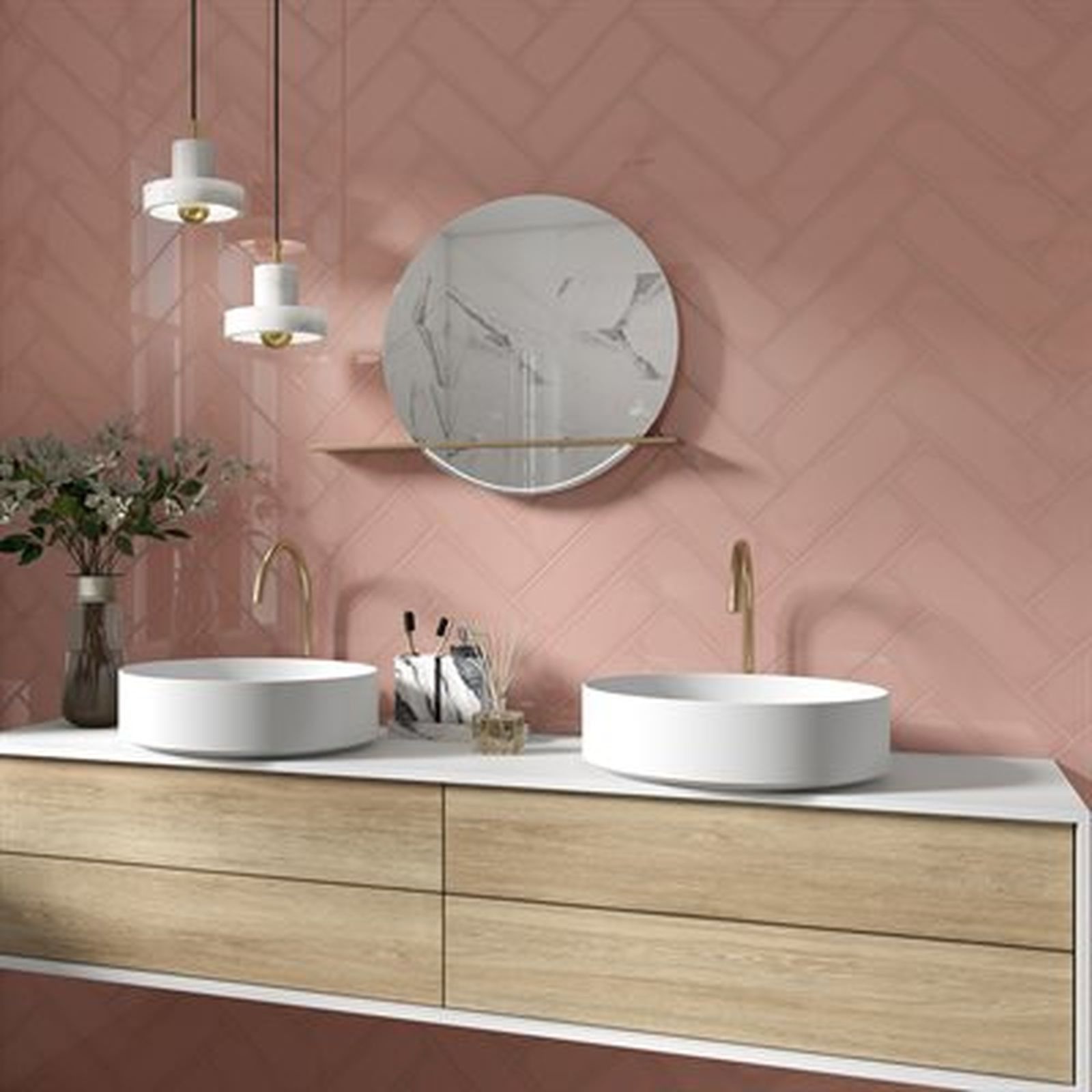 Bathroom with pink herringbone-tiled walls, white sinks, wooden vanity, and a marble-patterned mirror.