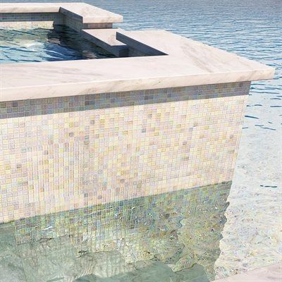 Swimming pool with mosaic tile wall and marble edge, water reflects the colors.