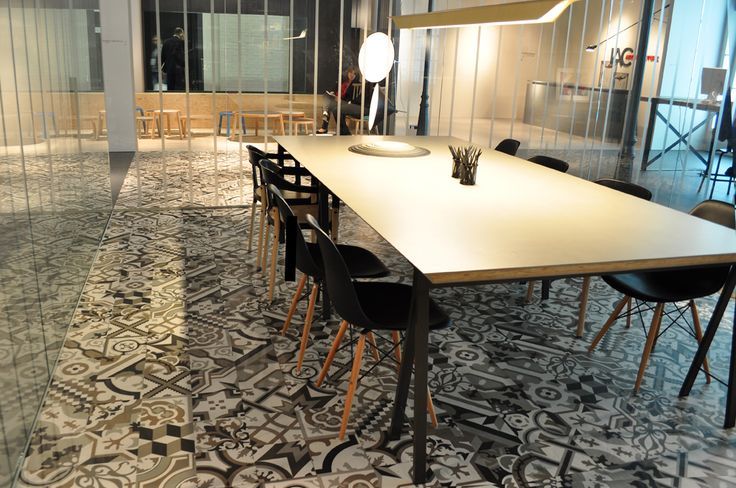 Conference room with long table, black chairs, patterned floor, and glass walls.