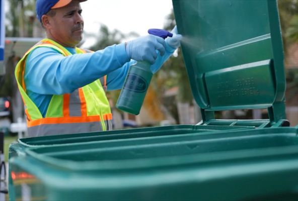 man spraying trash bin