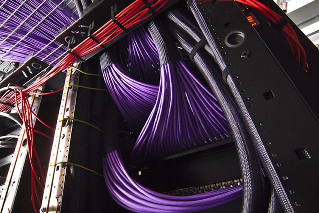 Un montón de cables morados y rojos cuelgan de un estante.