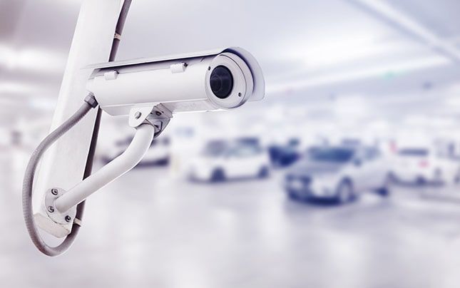 Una cámara de seguridad cuelga del techo de un aparcamiento.