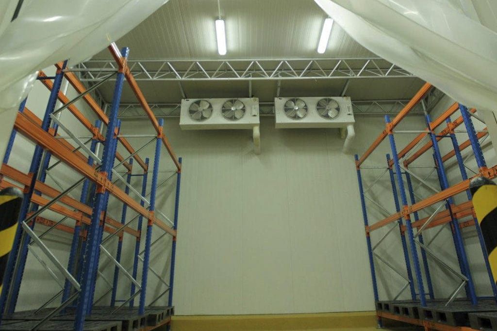 Un almacén con muchas estanterías y ventiladores en el techo.