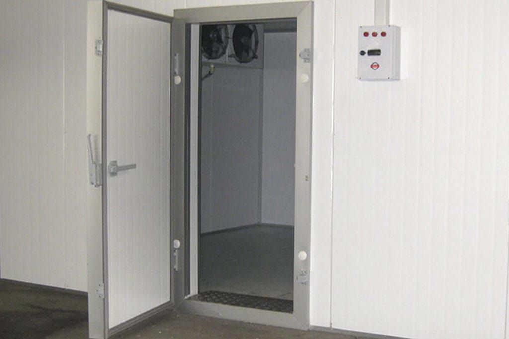 Hay una puerta abierta en una habitación con dos ventiladores en la pared.