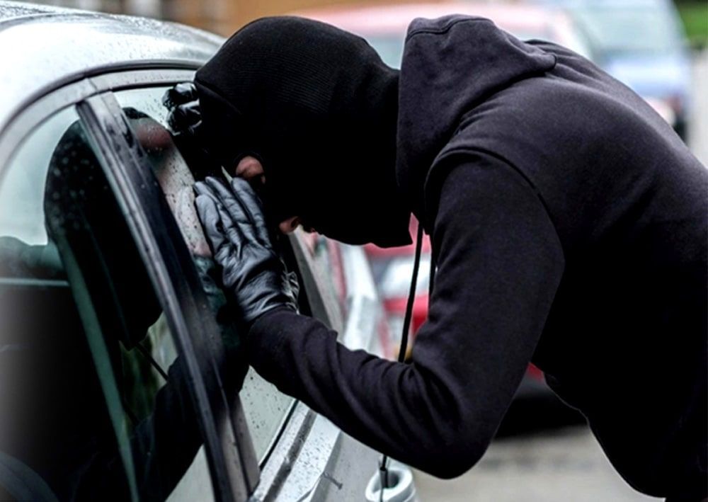 Un hombre enmascarado intenta entrar en un coche.