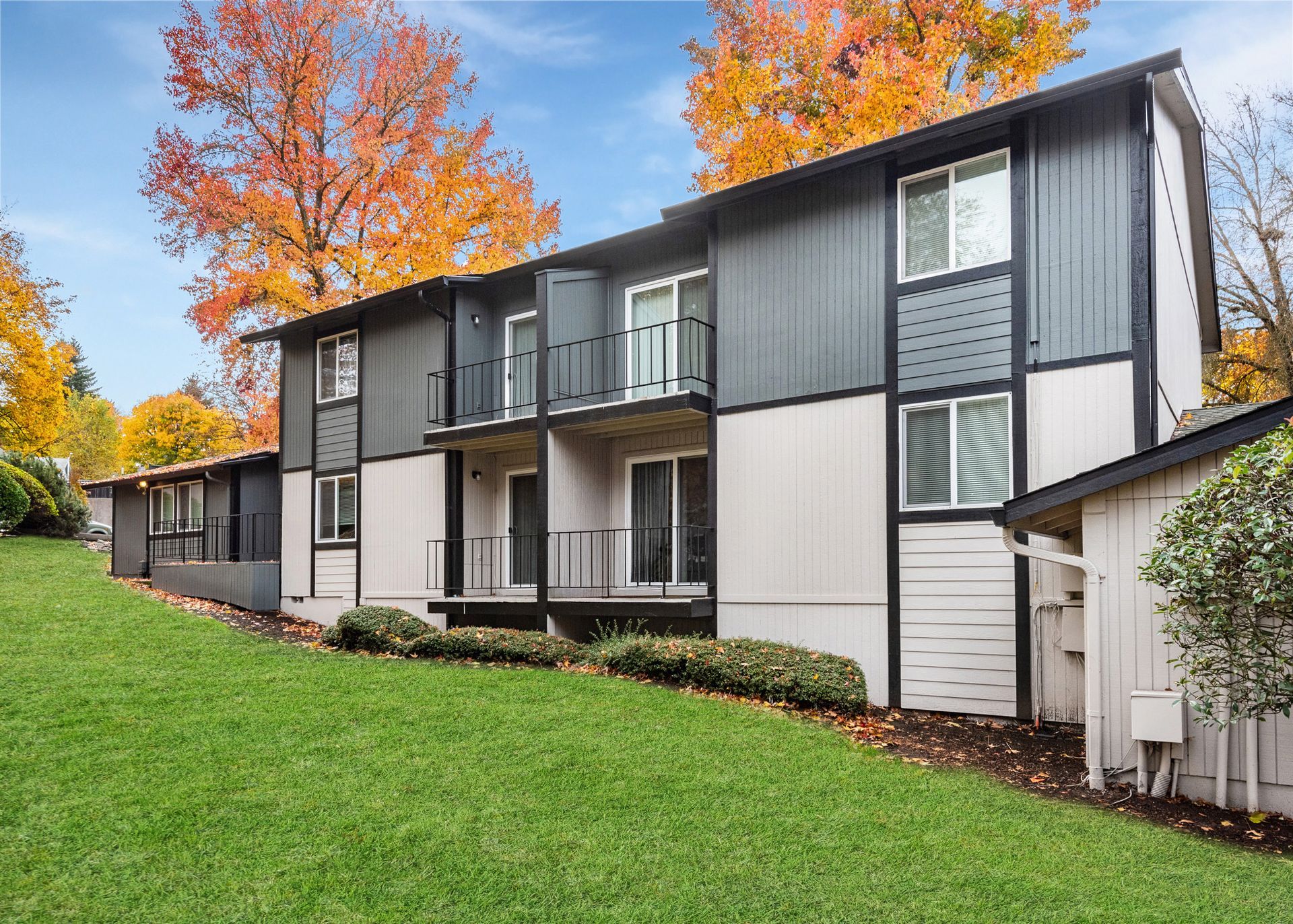 Exterior view of a multi-unit apartment building with balconies and autumn trees.