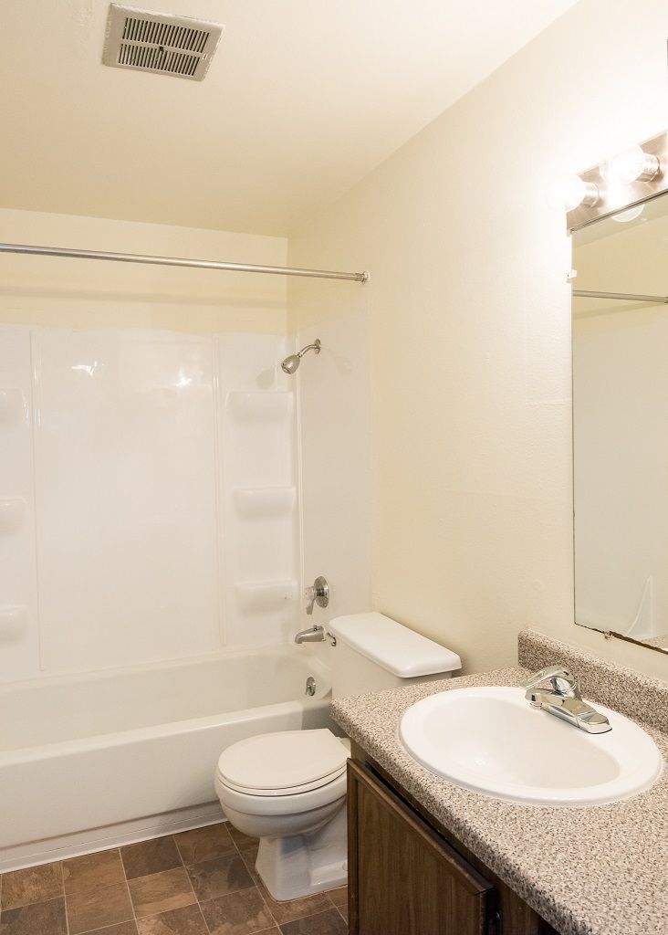 Bathroom in an apartment with a bathtub/shower, toilet, and sink.