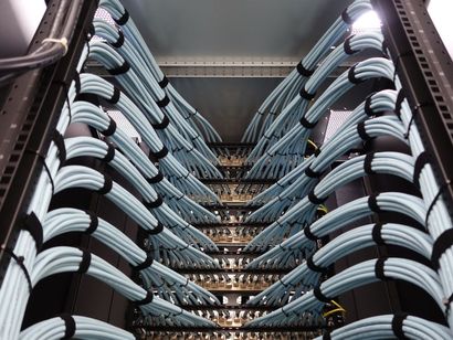 Neatly bundled light-blue ethernet cables connected to a server rack patch panel.