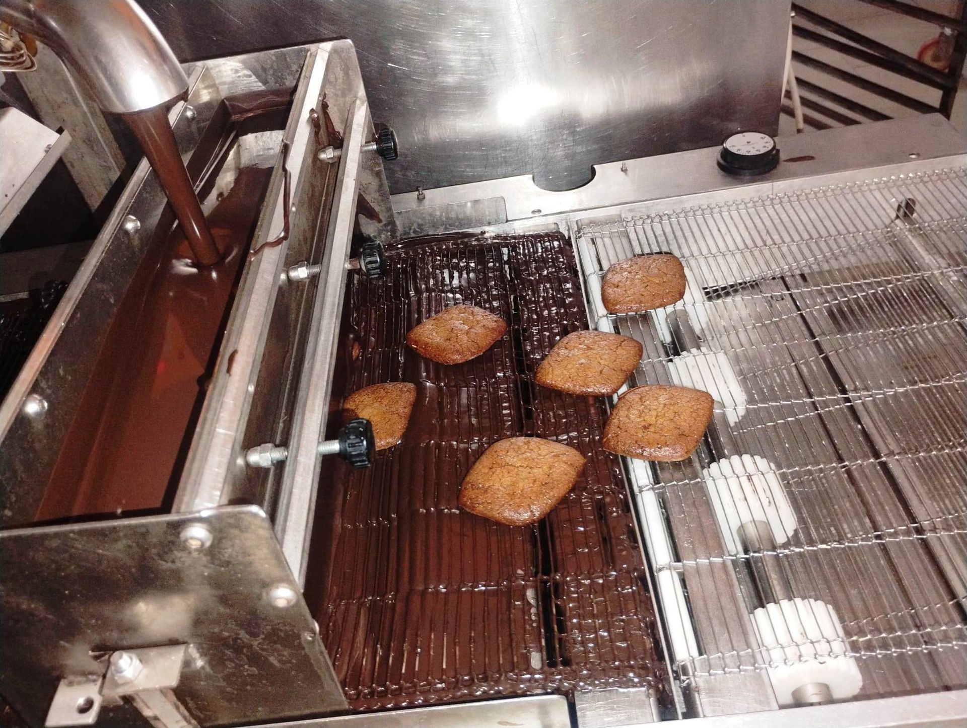 Cioccolato versato sui biscotti su una linea di produzione automatizzata.