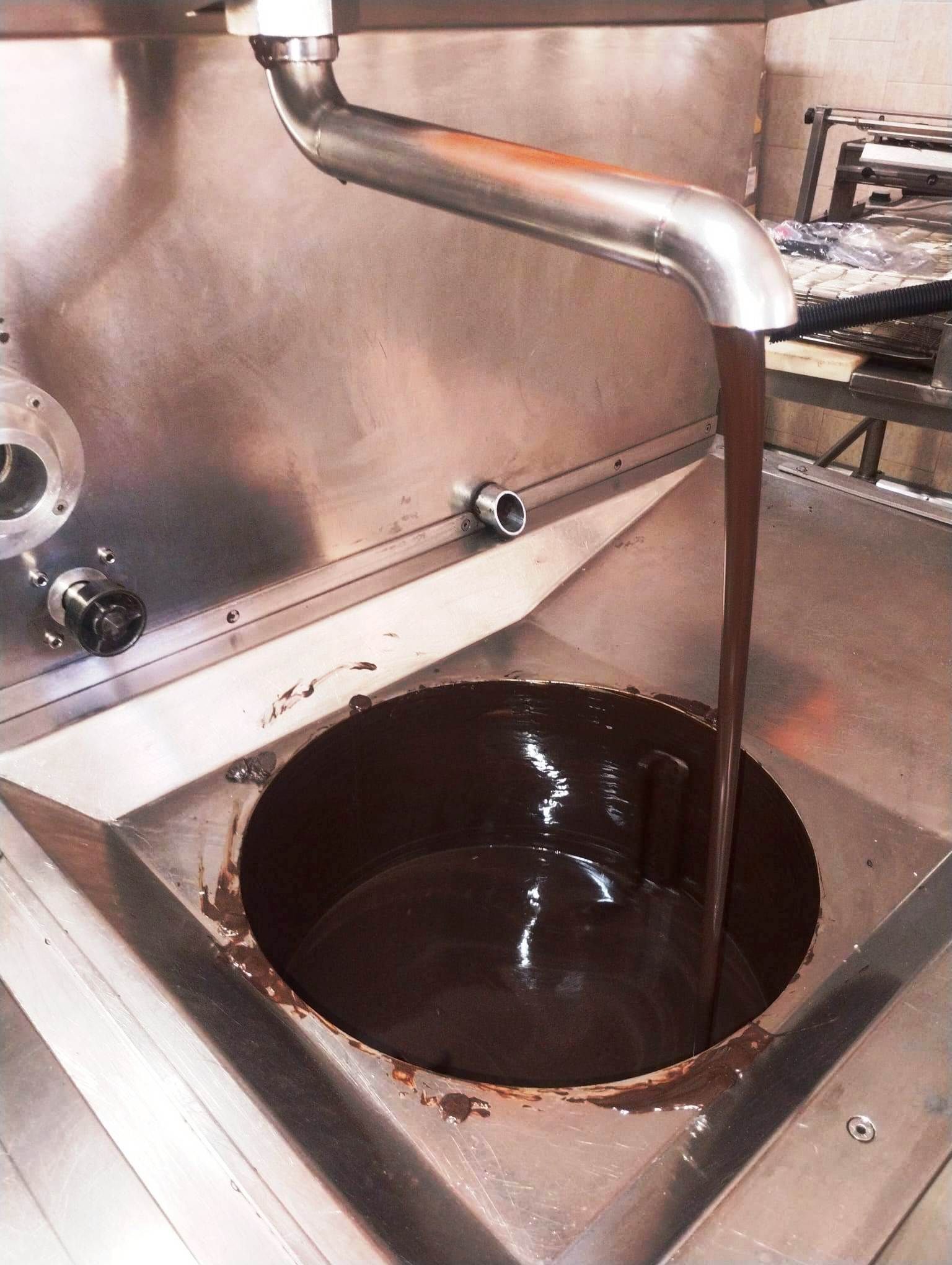 Il cioccolato viene versato da un tubo di acciaio inossidabile in una vasca rotonda.