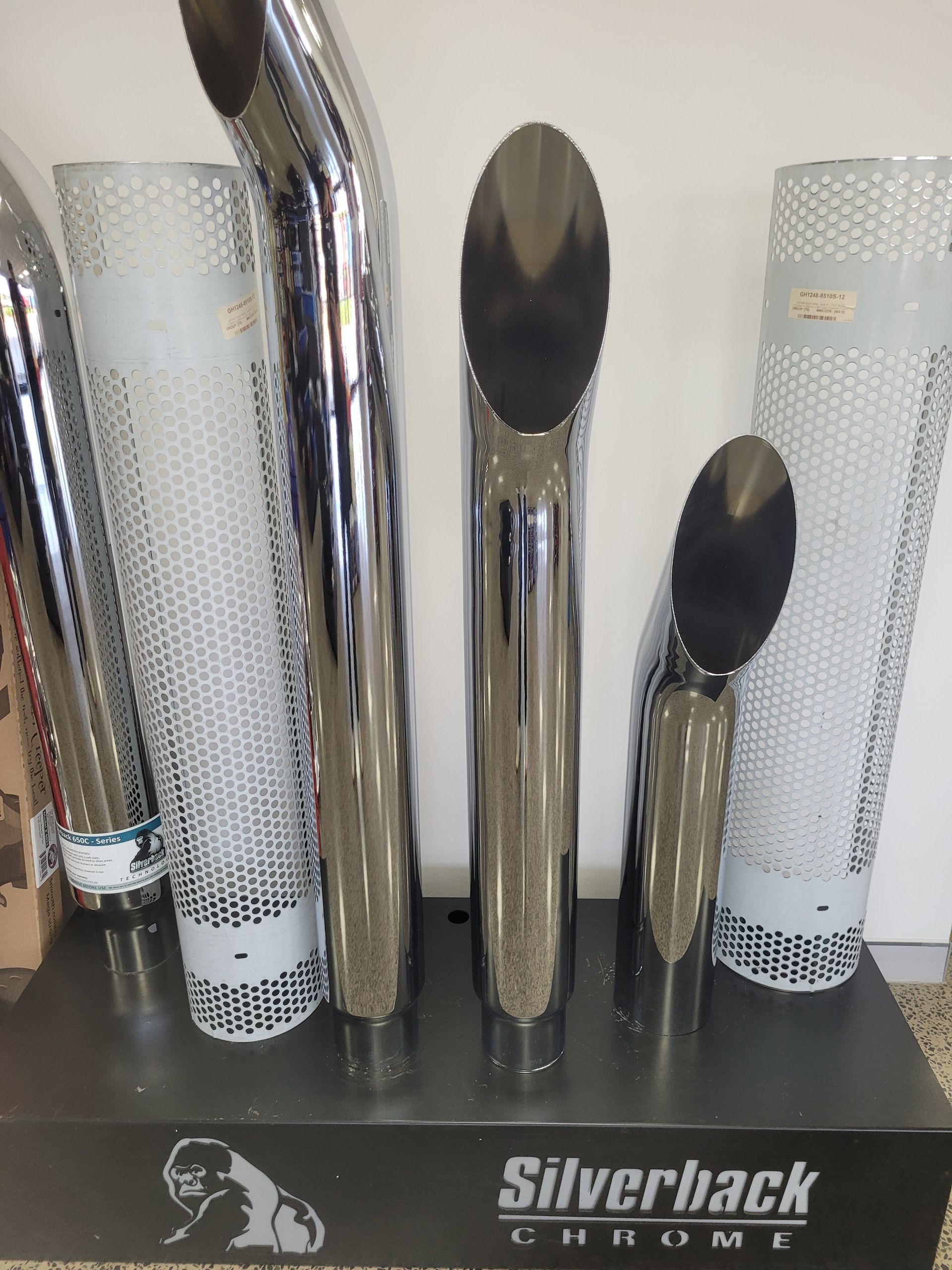 Chrome exhaust pipes and perforated metal covers displayed on a stand — Top End Diesel In Wishart, NT